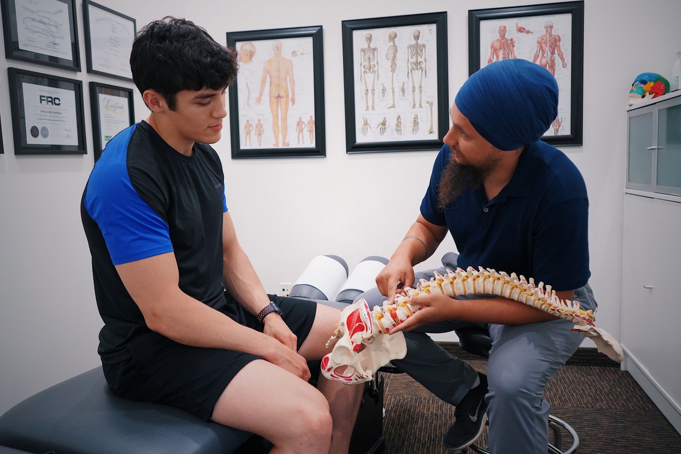 Chiropractor explaining a spine model to a patient