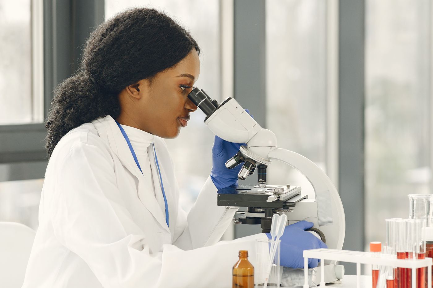 Scientist in a white lab coat looking through a microscope
